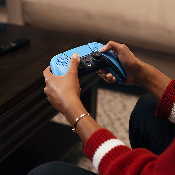 Eine Person mit einem blauen Gamecontroller, bereit, ein Videospiel zu spielen.